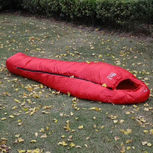 Red sleeping bag on grass with fallen leaves