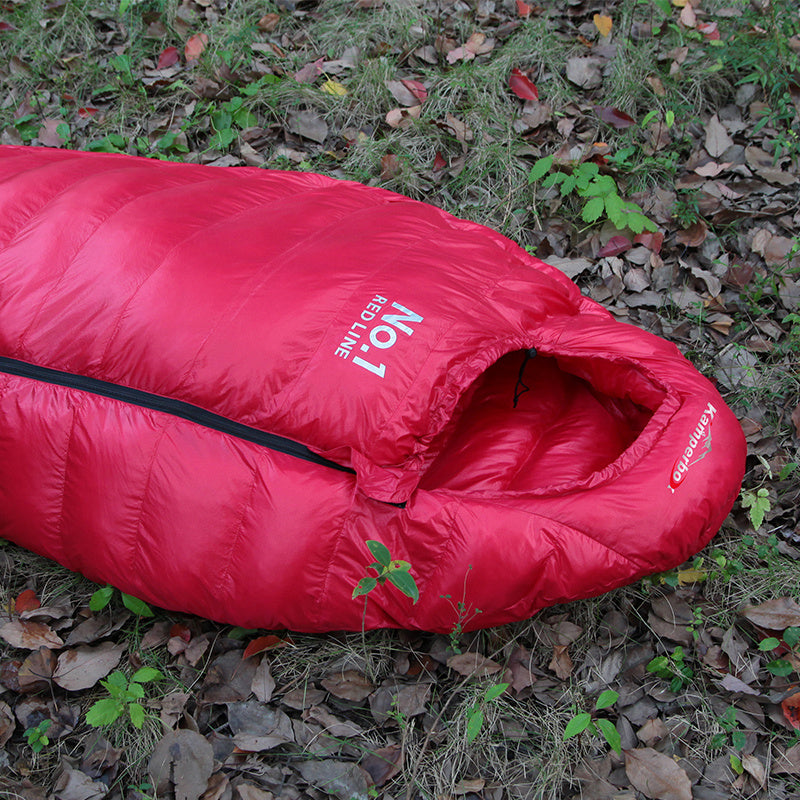 Load image into Gallery viewer, Red sleeping bag on the ground with visible branding
