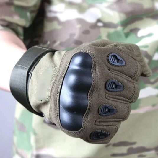 Brown tactical glove with black padding on a camouflage background