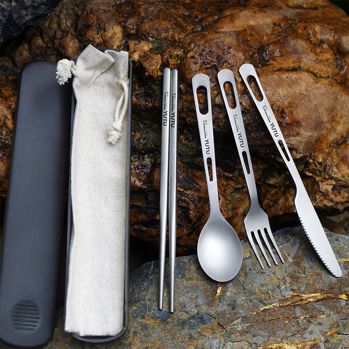 Set of stainless steel cutlery with case on a stone surface
